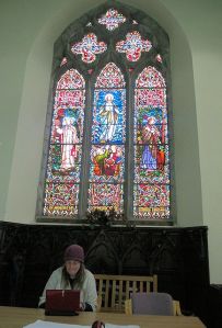 The stained-glass window and Shari at the table. Photo by Bill Burke.